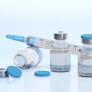 Syringe and a couple small bottles filled with liquid medicine. 