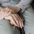 an elderly person's hands holding a cane