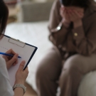 Patient with head in hands talking to doctor taking notes on a clipboard