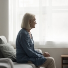 Senior female staring out window looking sad