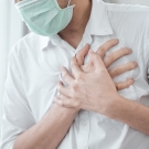 person wearing a mask and clutching their heart