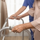 senior citizen walking with walker and healthcare provider