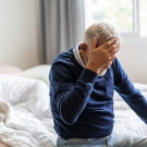man with head in hands on bed