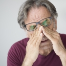 older man rubbing his eyes