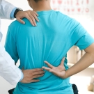 person clutching back with doctor checking them