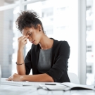 Woman in a blazer holding her head in pain during a migraine. 