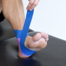Male patient using kinesio tape on ankle injury