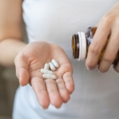 Person shaking pills into their hand from a bottle