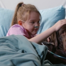 girl in hospital bed with therapy dog