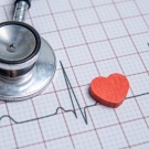 Electrocardiogram reading on paper with a stethoscope and red heart