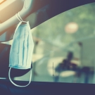 Medical mask hanging from the handle inside a car