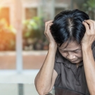 Older woman clutching her head in her hands