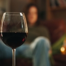 man in background staring at a glass of wine in foreground