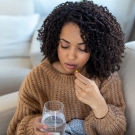 woman taking pills with a glass of water