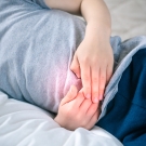 child on bed touching stomach