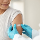 doctor putting a band-aid over a shot on a young woman's arm
