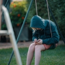 preteen using cell phone while sitting on a swing