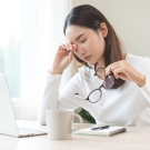 woman looking tired in front of her laptop