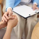 Woman with clipboard holding someone's hands