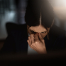 woman in the dark holding her head