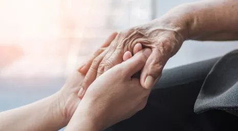 hands of an older patient holding younger hands