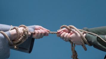 Two hands pulling on a rope in a tug of war. 