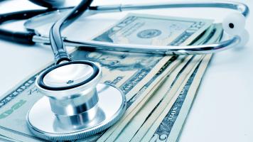 A stethoscope on a small pile of dollar bills.