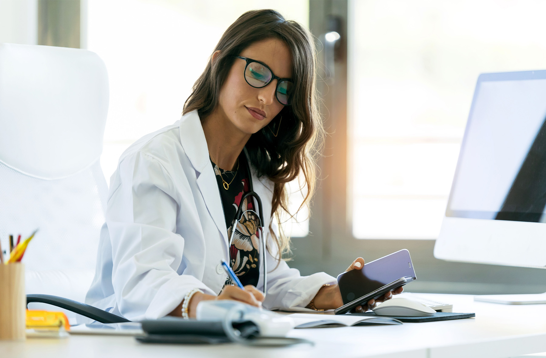 Healthcare professional taking notes at a desk.