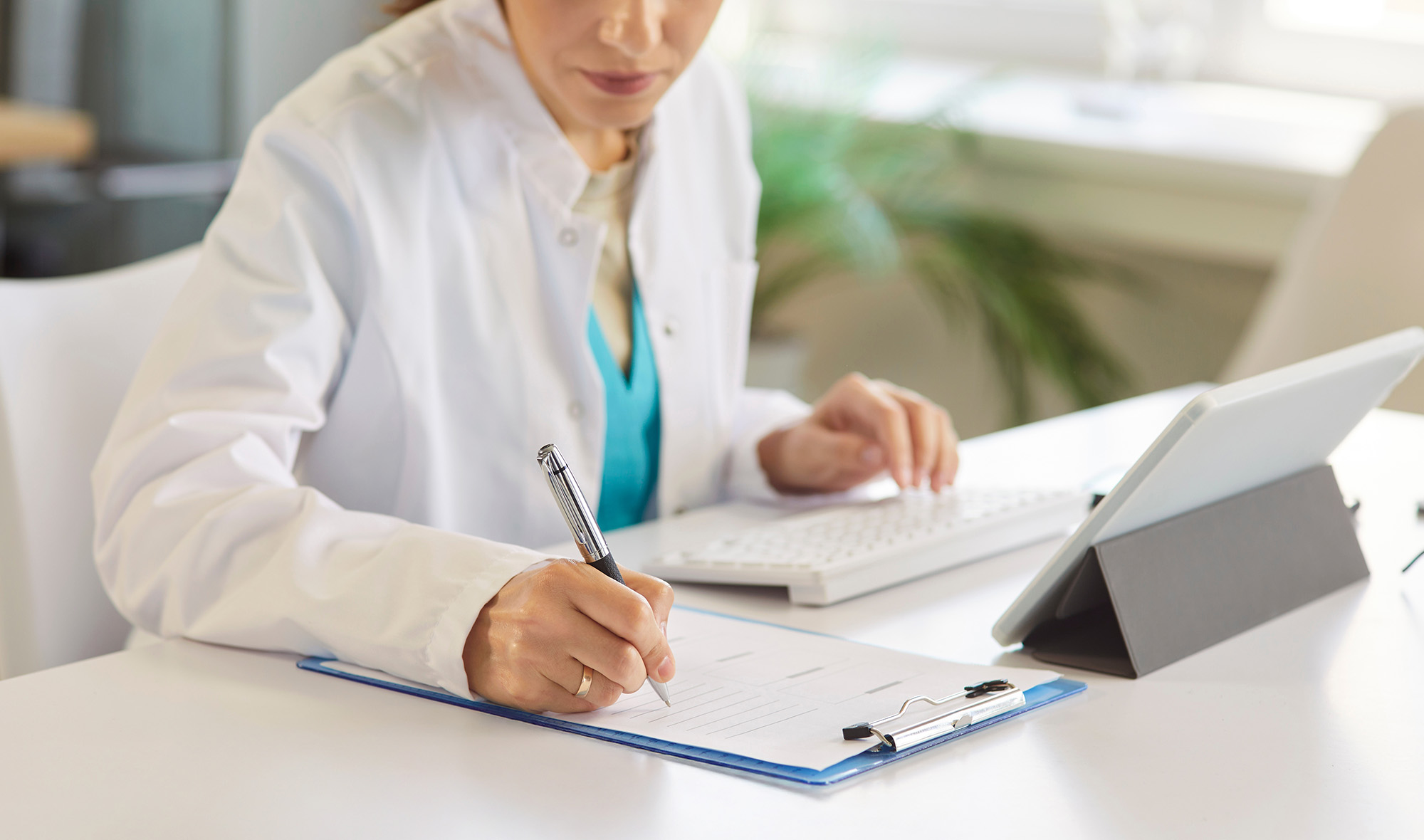Dermatology clinician taking notes while watching live broadcast on computer