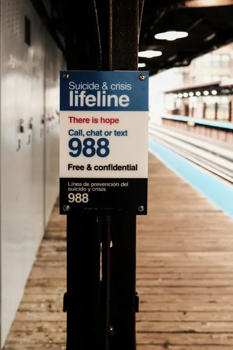 Subway platform with a sign advertising 988 that reads.