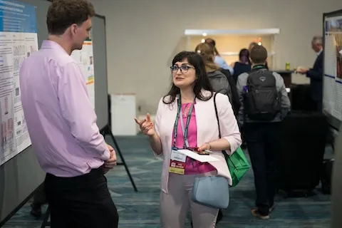 Man and woman talking to each other about research during the SAWC Spring conference.