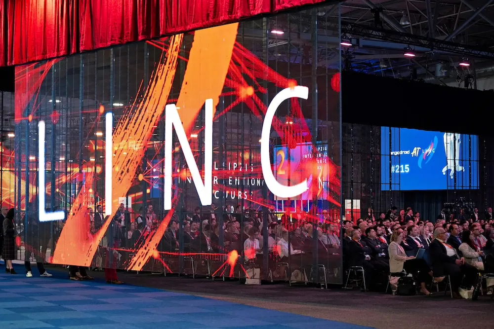 Full conference room of people watching a live case demonstration on the big screen