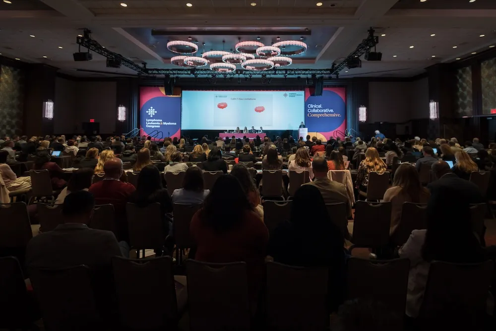 Full room of people at a conference listening to the main stage presentation