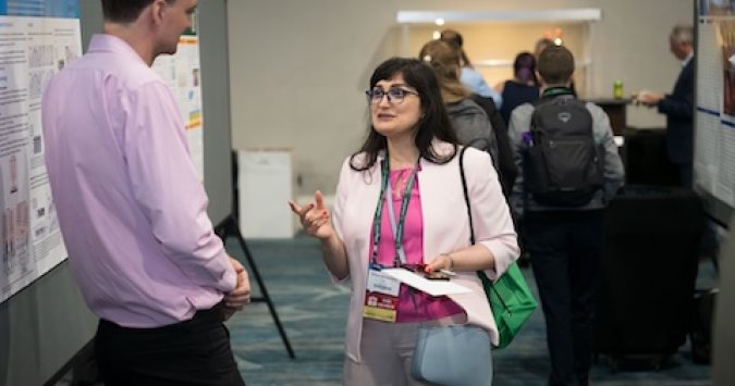 Man and woman talking to each other about research during the SAWC Spring conference.