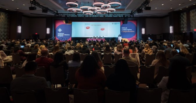 Full room of people at a conference listening to the main stage presentation